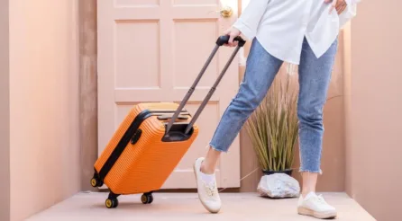 dame loopt deur uit met kleine oranje koffer voor een korte reis